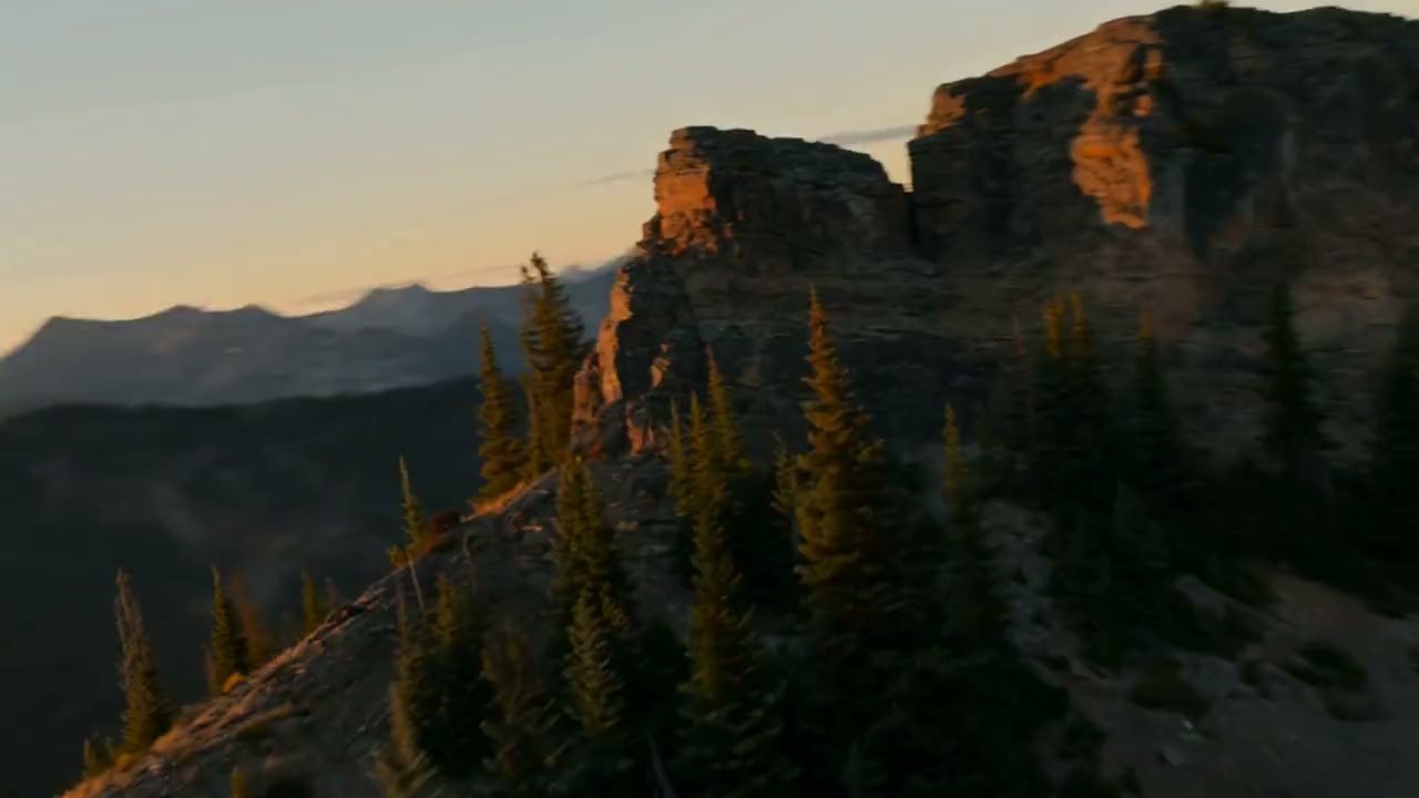 A forested ridge at sunset, the light low over a range of valleys